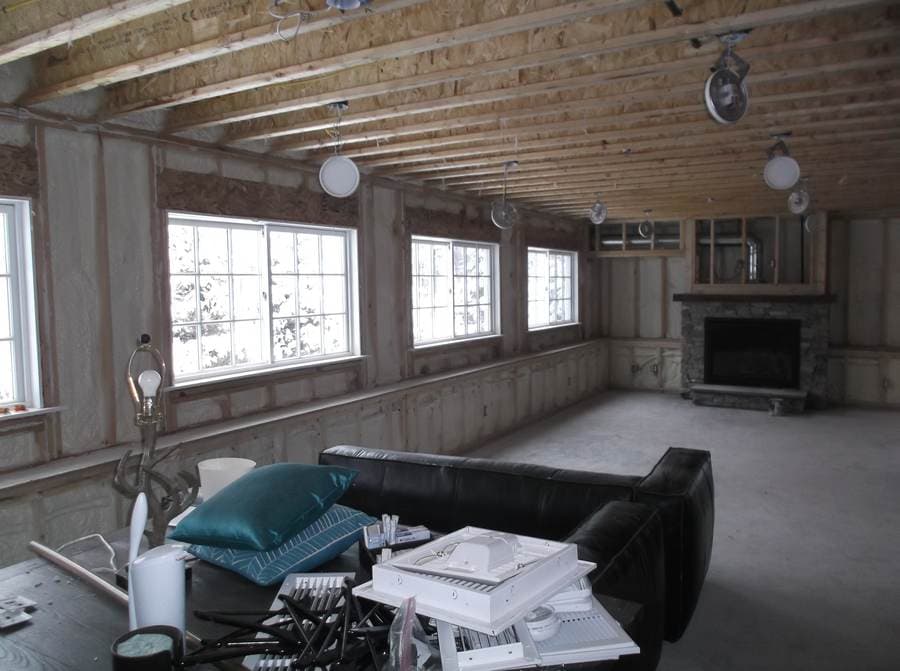 Room stripped to studs and spray foam insulation mid-rebuild, stone fireplace visible
