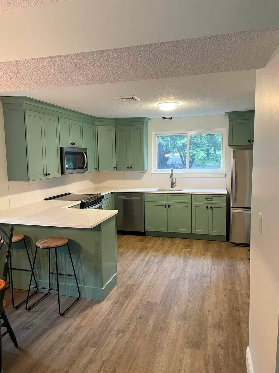 Fully rebuilt kitchen with sage green cabinets after a loss